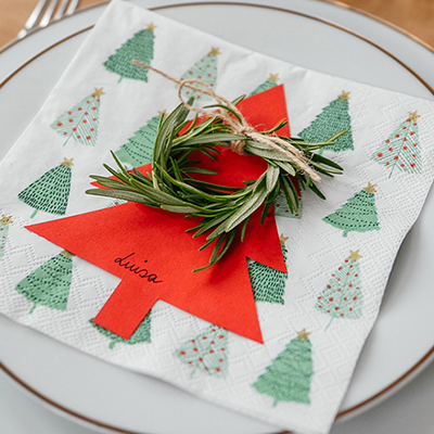 Eine Tannenbaum-Serviette, ein roter Papiertannenbaum und ein Rosmarin-Kranz