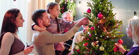 Zwei Erwachsene und ein Kind beim Anschauen eines Christbaumes