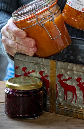 Eine alte Person stellt Marmeladengläser in eine Blechbox