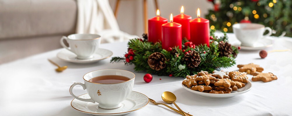 Ein gedeckter Tisch im Advent mit weißem Tisch, Teetassen, Lebkuchen und Adventkranz