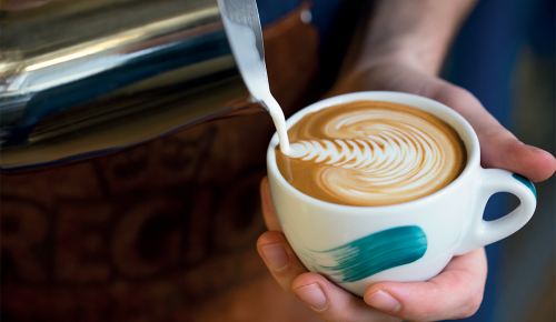 Milch wird in eine Tasse REGIO Kaffee geschüttet