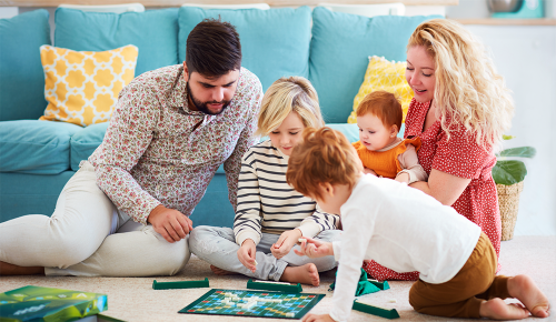 Eine Familie mit Kindern beim Spielen eines Spiels am Boden