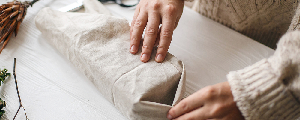 Einschlagen von Tuchenden eines Furoshiki-verpackten Geschenks