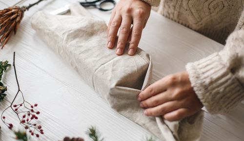 Einschlagen von Tuchenden eines Furoshiki-verpackten Geschenks