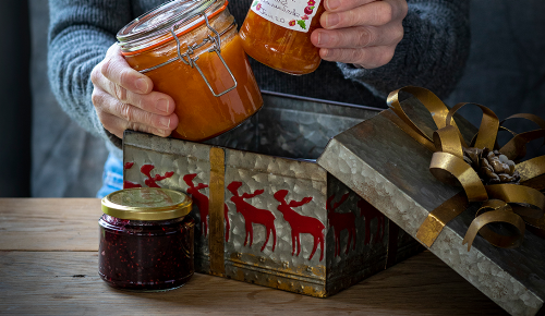 Eine ältere Person stellt Marmeladengläser in eine Keksdose