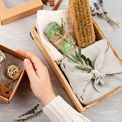Eine Person tut mehrere Hygieneartikel, wie Seifen, in eine Geschenkbox