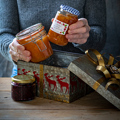 Eine ältere Person stellt Marmeladengläser in eine Keksdose
