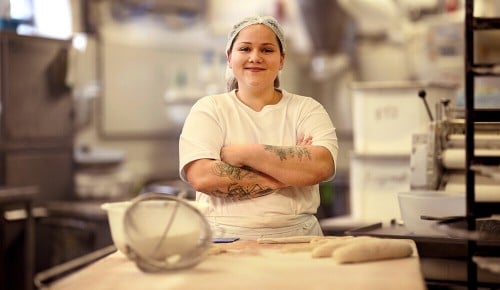 Eine Mitarbeiterin in der INTERSPAR Bäckerei lächelt in die Kamera