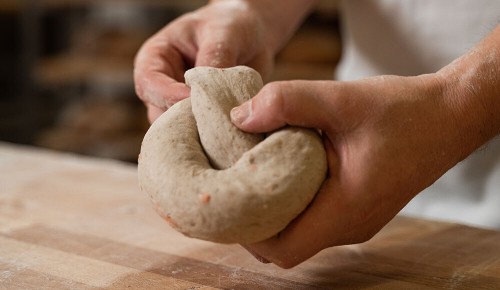 Eine Mitarbeiter:in einer INTERSPAR Bäckerei beim Knoten eines Teiges