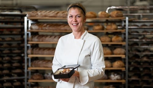 Eine Bäckerei-Mitarbeiterin von INTERSPAR hält ein Brot in den Händen und lächelt in die Kamera