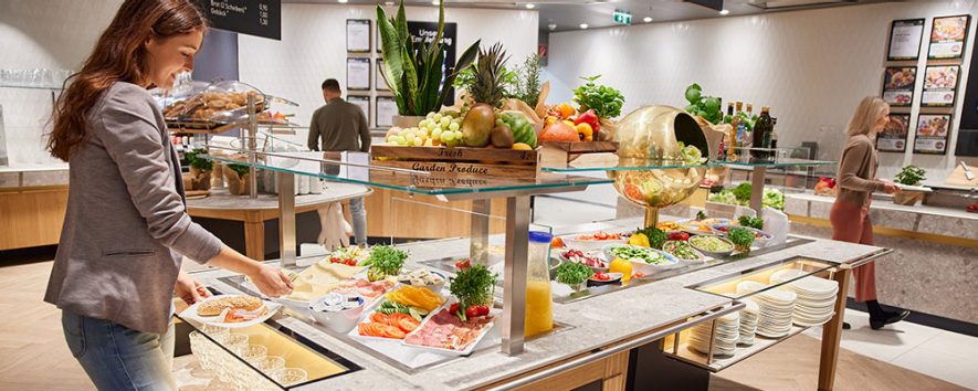 Eine Frau bedient sich an einem INTERSPAR Mittagsbuffet