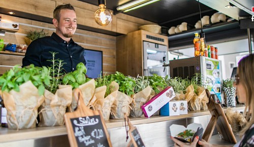 Eine Person holt sich beim INTERSPAR Foodtruck etwas zu essen