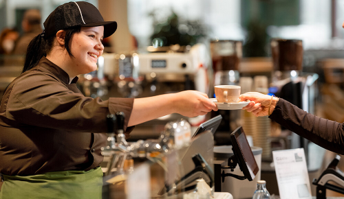Eine INTERSPAR-Mitarbeiterin gibt Kund:innen einen frischen Kaffee