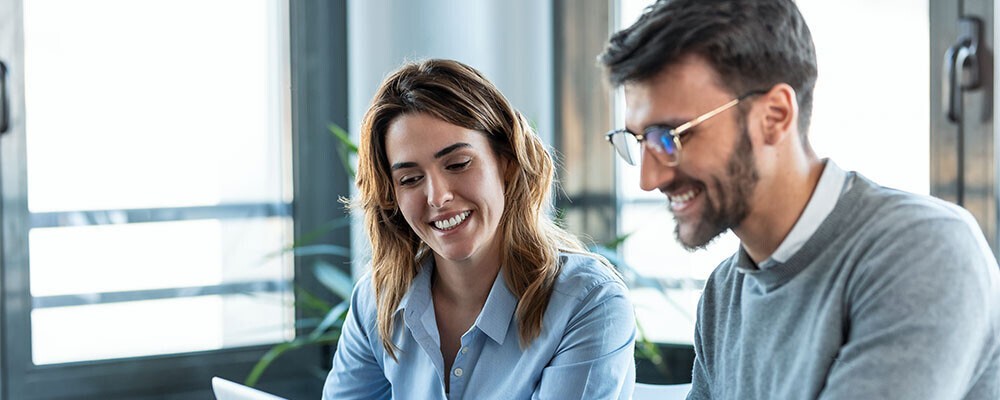 Ein Mann und eine Frau im Business-Outfit sitzen in einem Büro