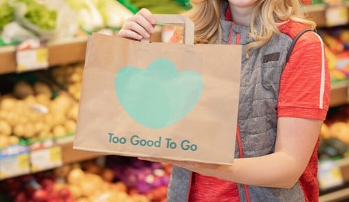 Eine Person mit einer Papiertasche mit der Aufschrift "Too good to go"