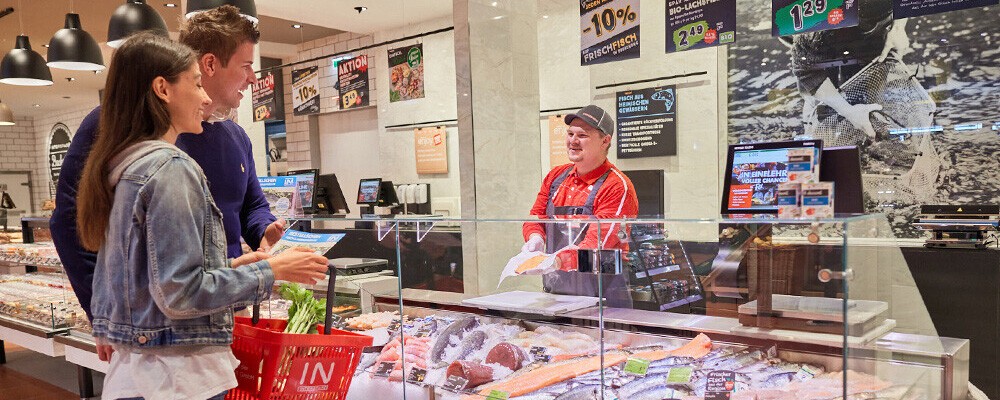 Zwei Personen beim Einkaufen an einer INTERSPAR-Fischtheke