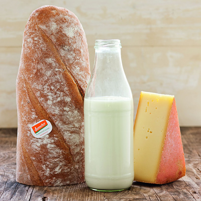 Ein halber Laib Brot, eine Glasflasche mit Milch und ein Stück Käse