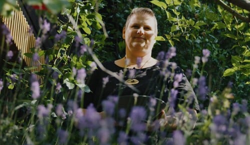 Eine Dame neben verschiedenen blühenden Blumen