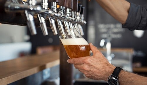 Eine Person beim Zapfen eines Bieres in ein Bierglas