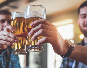 Zwei Personen beim Anstoßen mit vollen Biergläsern