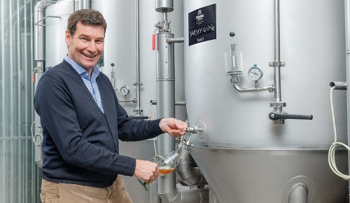 Ein Mitarbeiter von Zillertal Bier neben einem Bierkessel