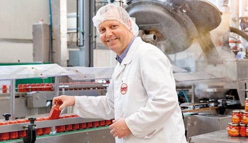 Ein Mitarbeiter der Delikatessen Manufaktur Frey neben einem Förderband