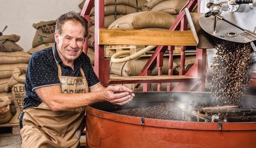 Ein Mitarbeiter von Mocafé neben einem großen Röstkessel