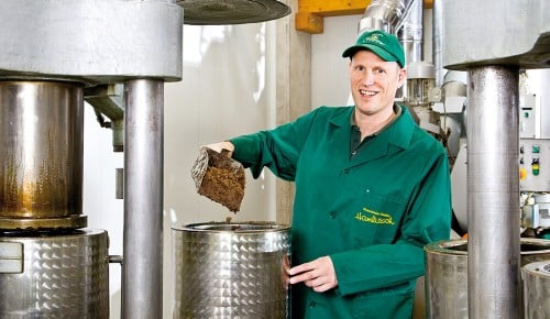Ein Mitarbeiter der Ölmühle Hamlitsch neben einer Ölpresse