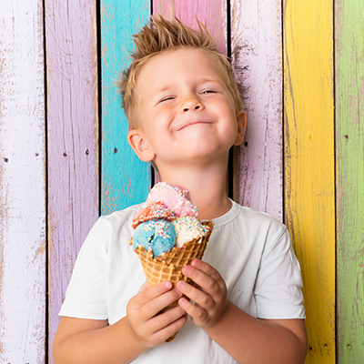 Ein kleiner lächelnder Junge mit einem großen Eis in den Händen