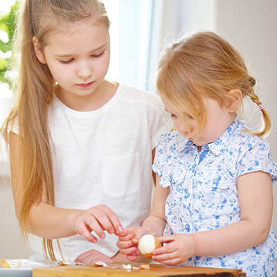 Zwei kleine Mädchen beim Schälen von hartgekochten Eiern
