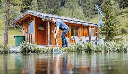 Ein Mitarbeiter von Grassner Fisch mit einem Kescher im Wasser