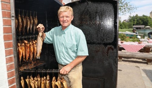 Ein Mitarbeiter der Schlossfischerei Fuschl mit vielen geräucherten Fischen