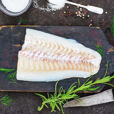 Ein Stück weißer Fisch auf einem dunklen Brett
