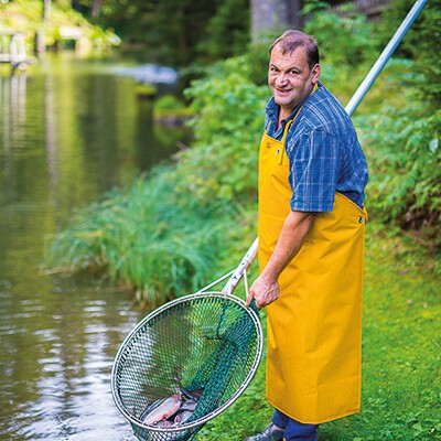 Ein Mitarbeiter der Fischerei Walter Vötter mit einem Kescher voller Fische
