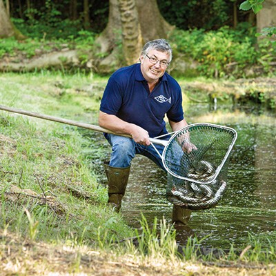 Ein Mitarbeiter der Fischzucht Haimel mit einem Kescher voller Fische