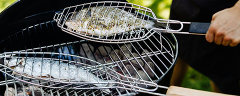 Fische in einer Grillzange auf einem Kugelgrill