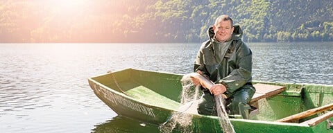 Ein Mitarbeiter von Wilder Fisch mit einem Netz in einem Boot