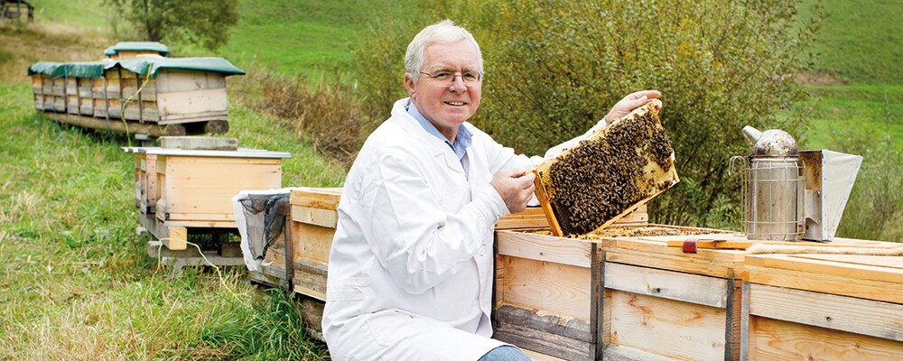 Ein Mitarbeiter der Imkerei Neber neben Bienenkästen