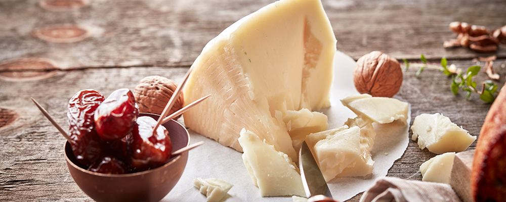 Ein mürber Hartkäse neben einem Käsemesser