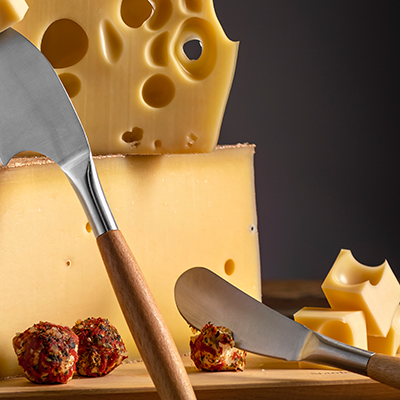 Ein Stück Löcherkäse auf einem Stüpck Hartkäse