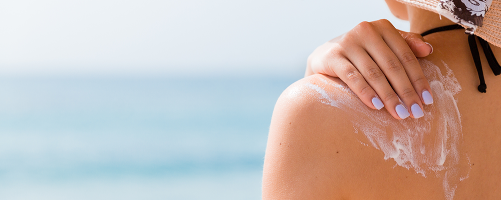 Kosmetik aus Österreich Eine Frau, die Sonnenmilch auf ihrer Schulter aufträgt