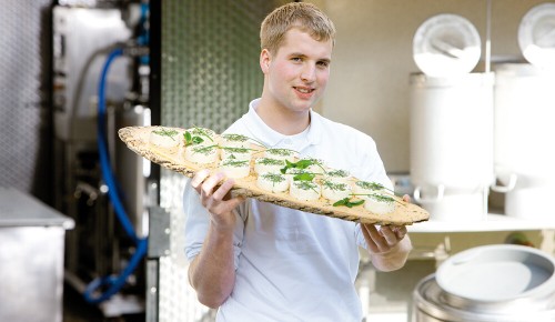 Ein Mitarbeiter von Metzler Käse & Molke beim Tragen von Molkeprodukten
