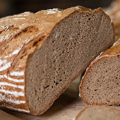 Ein halbiertes Roggenbrot auf einem Holzbrett