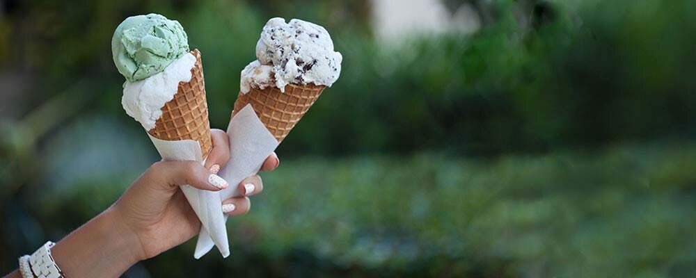 Eine Person hält zwei Eiswaffeln mit Eiskugeln in der Hand