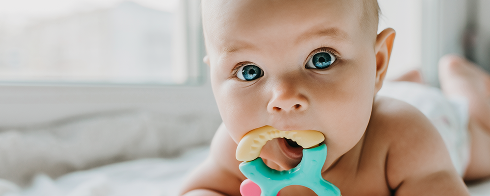 Ein kleines Baby mit großen blauen Augen mit einer Rassel in den Händen