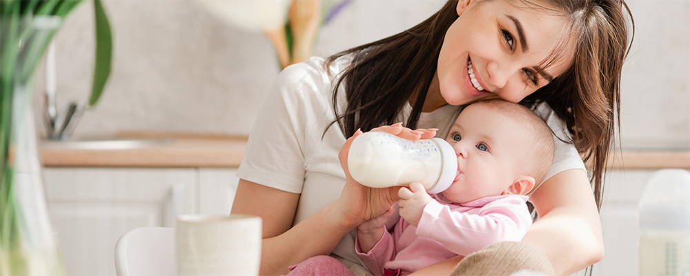 Eine Mutter füttert ein kleines Baby mit einer Flasche auf ihrem Schoß