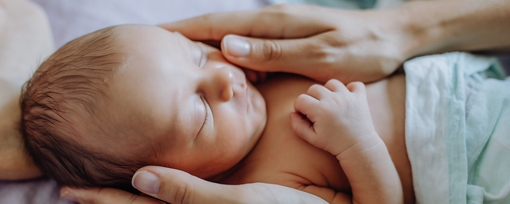 Ein neugeborenes Baby wird von den Händen der Mutter sanft gehalten