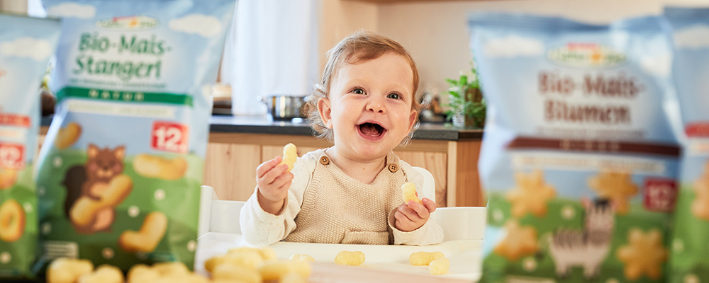 Ein kleines lachendes Mädchen beim Essen von SPAR Natur*pur Babynahrung