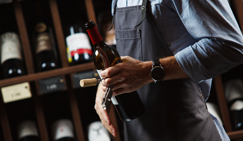 Ein Sommelier mit einer Flasche Rotwein in den Händen
