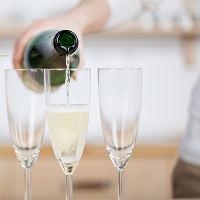 Eine Person schenkt Sekt aus einer Flasche in Sektgläser